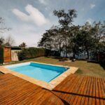 Scenic outdoor swimming pool surrounded by lush greenery and wooden decking, ideal for relaxation.