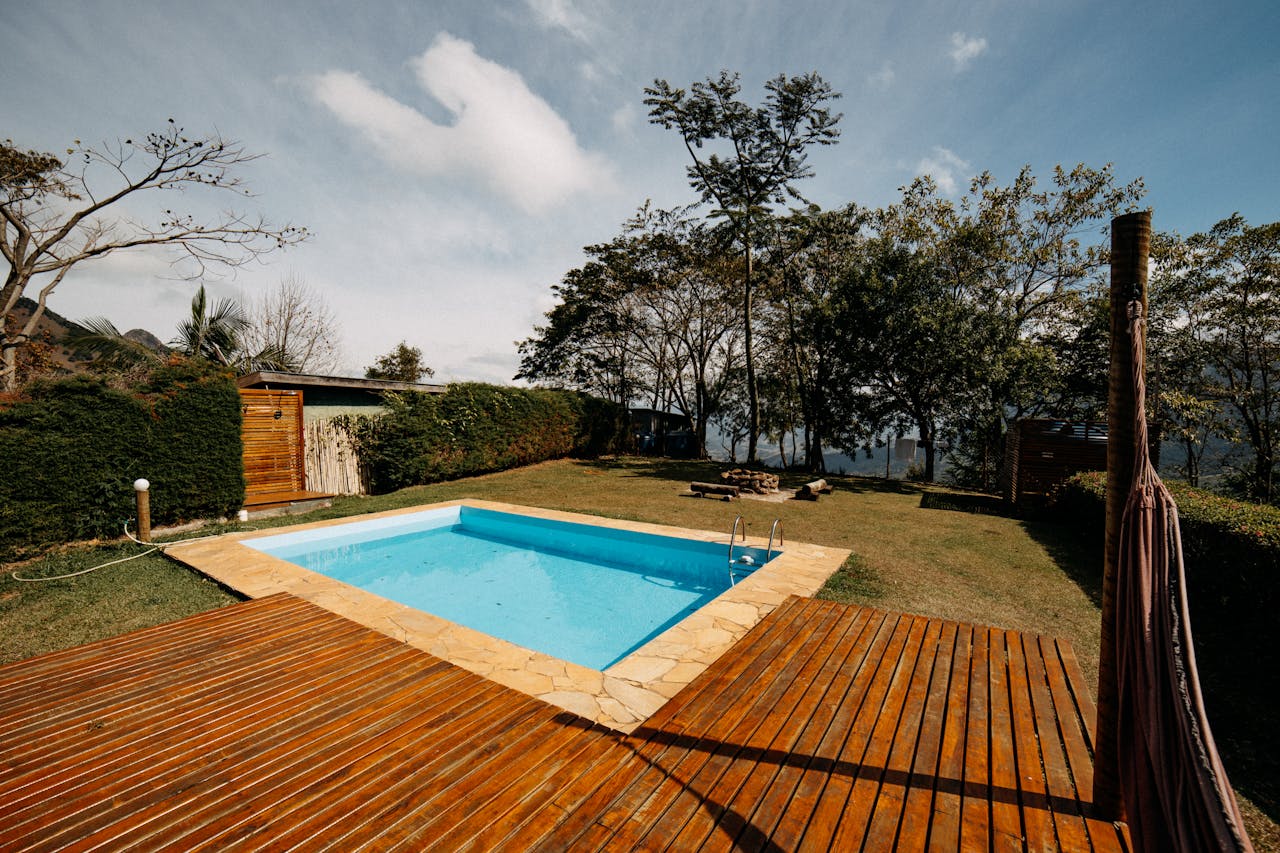 about-us-01 Scenic outdoor swimming pool surrounded by lush greenery and wooden decking, ideal for relaxation.